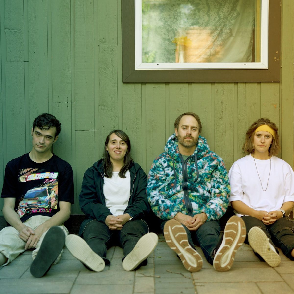 Little Super Dangerous — Julian, Jess, Jordan, and Jenna sitting against a green wall.